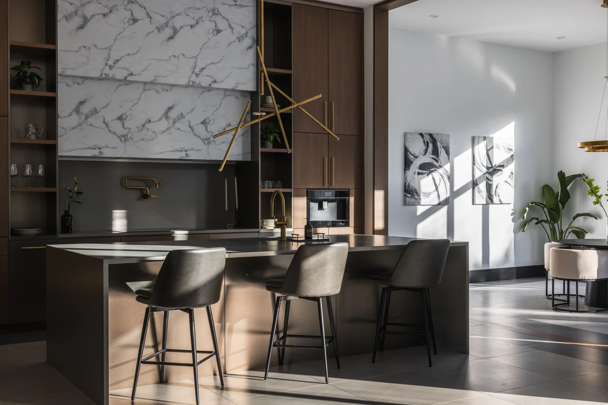 Kitchen island, built-in cabinetry, veined backsplash, and sculptural light fixture at Skyward