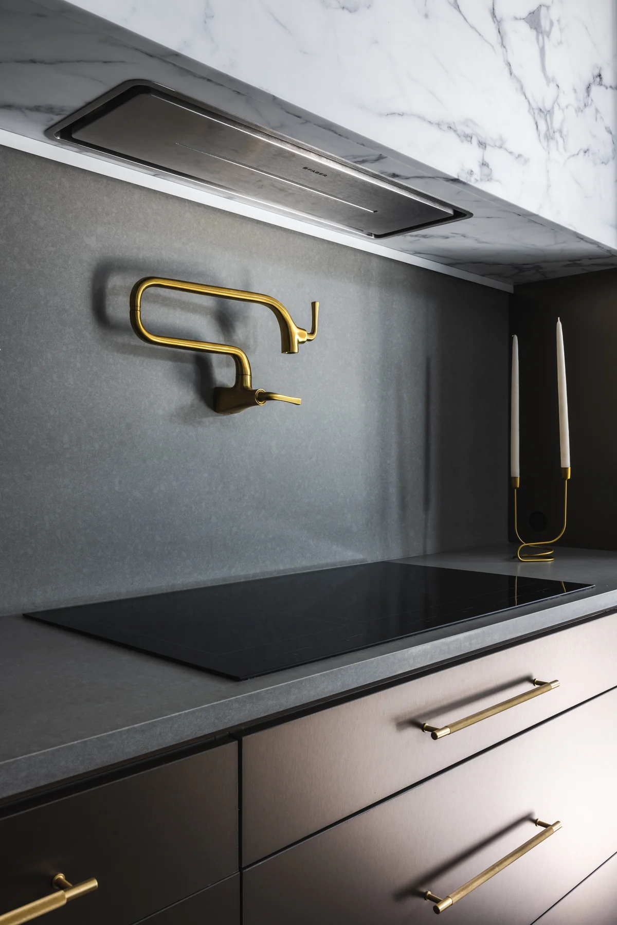 Close view of kitchen cabinetry, drawer hardware, countertop, and wall-mounted pot filler