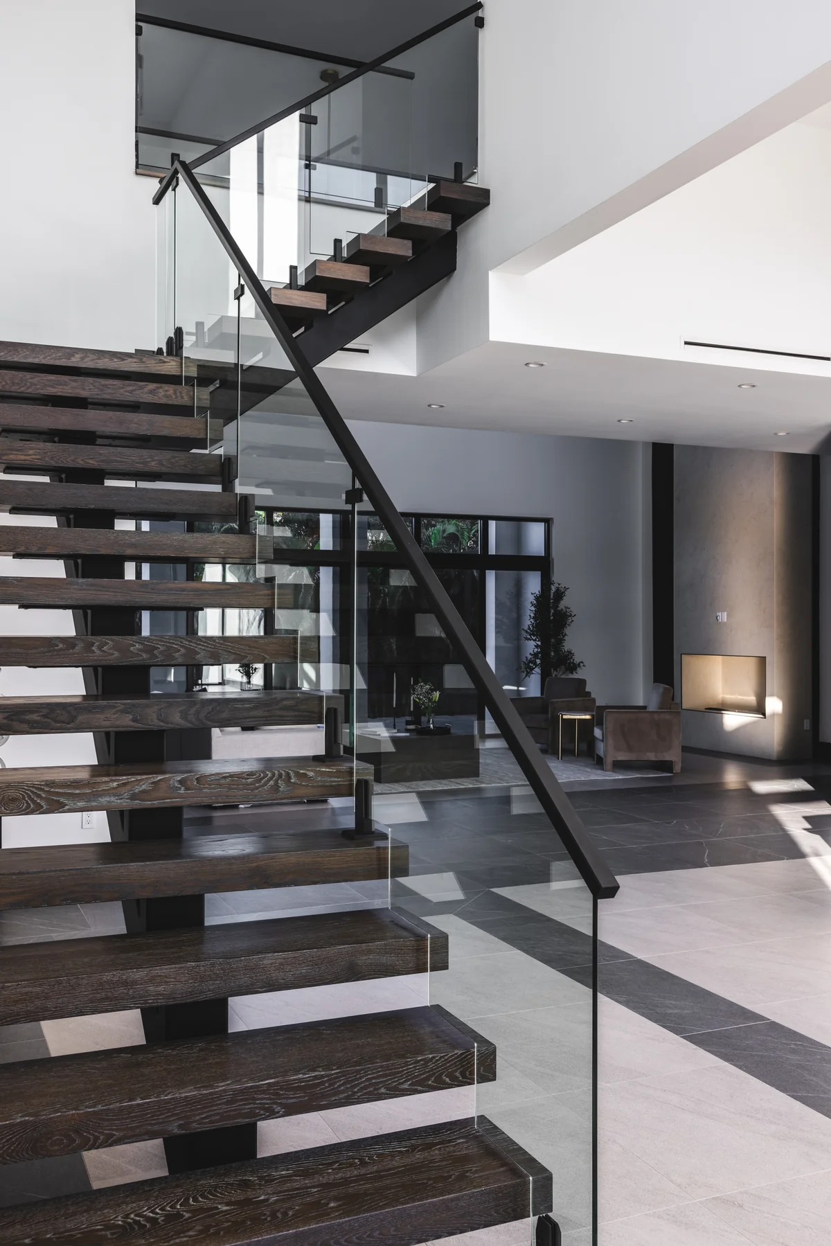 Open-riser stair with timber treads, dark structure, and glass balustrade